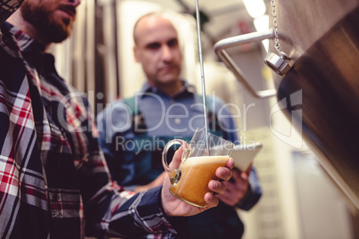 Owner pouring beer in glass at brewery