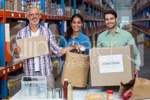 Three volunteers packing eatables in cardboard box