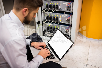 Technician using laptop while analyzing server