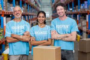 Portrait of three happy volunteers standing with arms crossed