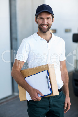 Portrait of happy delivery man holding parcel and clipboard