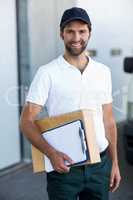 Portrait of happy delivery man holding parcel and clipboard