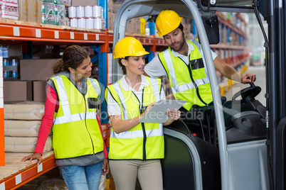 Male and female workers discussing over clipboard