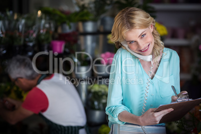 Smiling female florist taking an order on telephone