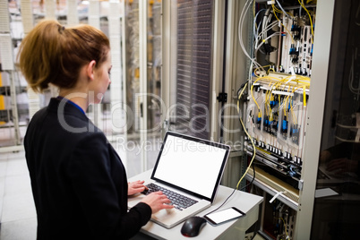 Technician using laptop while analyzing server