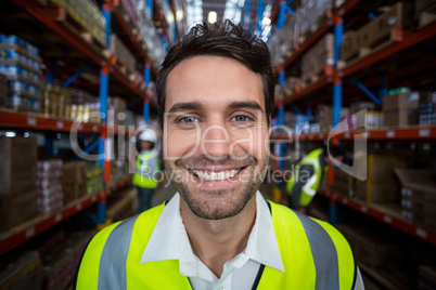 Happy warehouse worker holding clipboard