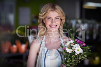 Happy female florist holding bunch of flowers in flower shop