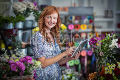 Smiling female florist using digital tablet