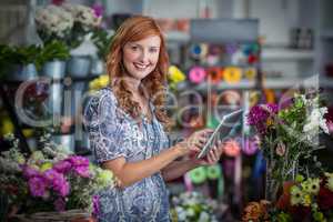 Smiling female florist using digital tablet