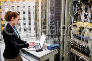Technician using laptop while analyzing server