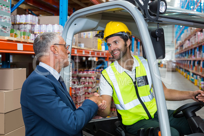 Warehouse worker shaking hands manager