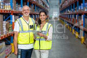 Portrait of warehouse workers standing with digital tablet