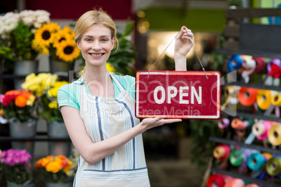 Female florist holding open signboard