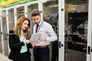 Technicians using digital tablet while analyzing server