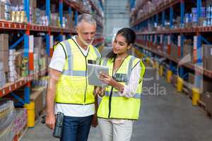 Warehouse workers discussing with digital tablet