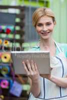 Happy female florist using digital tablet