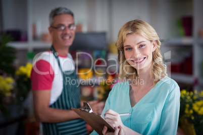 Smiling female florist noting on clipboard at flower shop