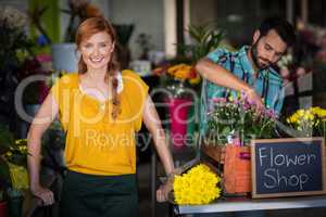 Female florist standing while male florist arranging flower bouquet