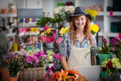 Smiling florist using laptop in flower shop