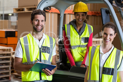 Portrait of warehouse workers and forklift driver