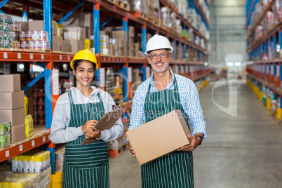 Portrait of warehouse workers standing with clipboard and cardboard boxes