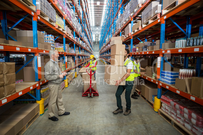 Manager looking at the worker carrying cardboard boxes