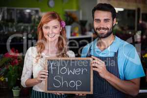Portrait of couple holding slate with flower shop sign