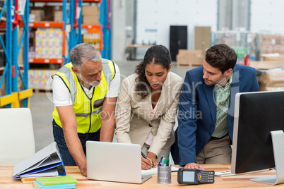 Warehouse managers and worker discussing with laptop