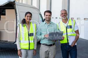 Manager and warehouse workers standing with laptop and clipboard