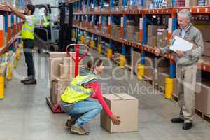 Warehouse manager showing thumbs up to female worker while carrying cardboard boxes