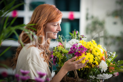 Happy female florist holding basket of flowers