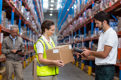 Female worker holding cardboard box while male worker scanning barcode
