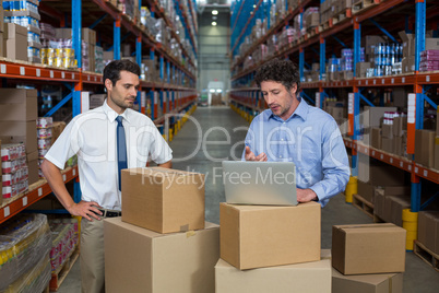 Warehouse workers discussing with laptop Warehouse workers discussing with laptop