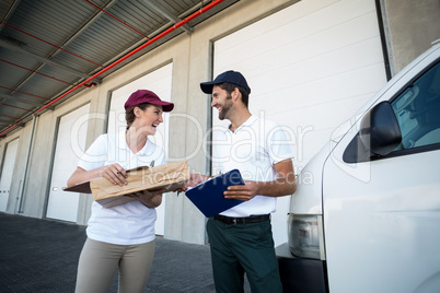 Happy delivery man and woman standing with clipboard and parcel