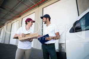 Happy delivery man and woman standing with clipboard and parcel