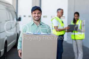 Portrait of delivery man carrying cardboard box