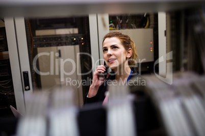 Technician talking on mobile phone in server room