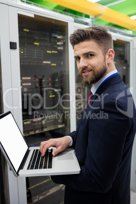 Technician using laptop while analyzing server