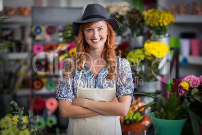 Happy female florist standing with arms crossed in flower shop