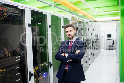 Technician standing with arms crossed in a server room