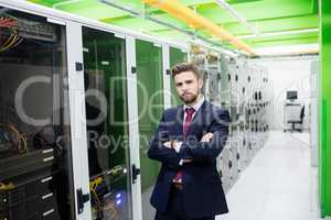 Technician standing with arms crossed in a server room