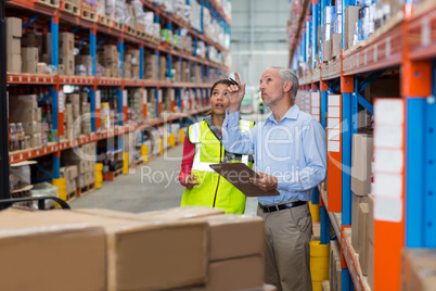 Warehouse manager and female worker interacting while checking inventory