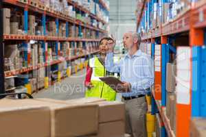 Warehouse manager and female worker interacting while checking inventory