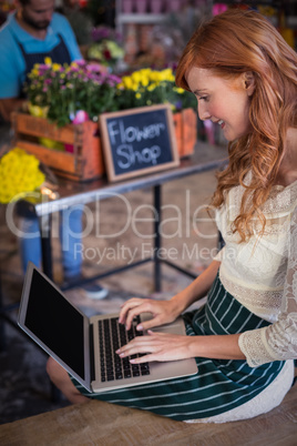 Female florist sitting and using laptop