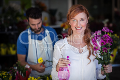 Woman holding bunch of flowers while man preparing flower bouquet