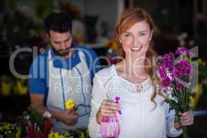 Woman holding bunch of flowers while man preparing flower bouquet