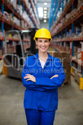 Portrait of female warehouse worker standing with arms crossed