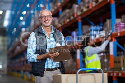 Warehouse manager smiling and holding clipboard