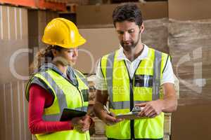 Warehouse workers discussing with clipboard and digital tablet