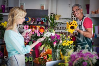 Smiling florist spraying water on flowers in flower shop